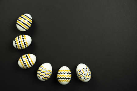 Golden, black, white easter eggs on a black background. Geometric. Minimal concept. Top view. Card with copy space for text.の写真素材