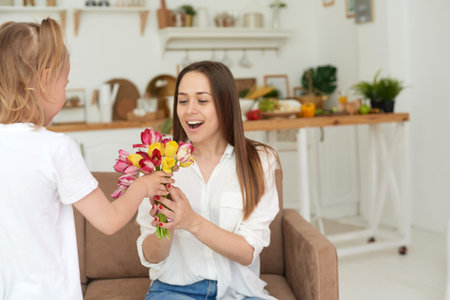 Happy mother accepts a gift from her little daughter. Congratulations on Mothers Day, birthday or Womens Day.の写真素材
