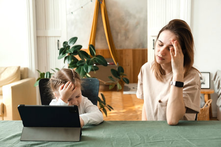 The little girl does not understand how to do homework or solve a problem. Stressed mother homeschooling with her child during coronavirus, Covid-19 outbreak quarantine. Self isolation, social distancing conceptの写真素材