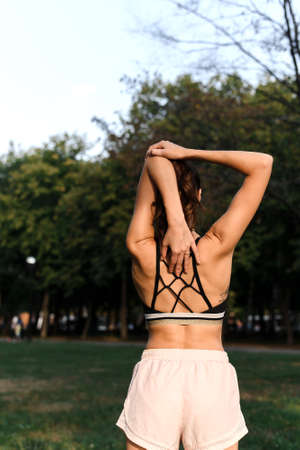 Young woman stretches her arms while doing sports in the parkの写真素材