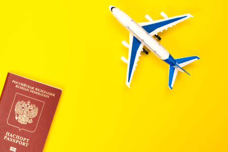 Foreign Russian passport and plane on a yellow background. Migration, moving to another country, refugees.の写真素材
