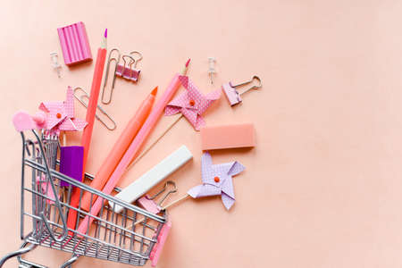 Stationery on a pink background in a shopping cart. Office supplies for schoolの写真素材