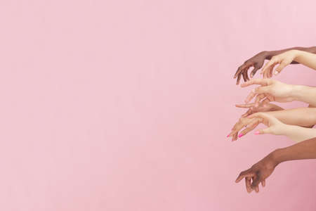 Art. African American and Caucasian hands showing on pink studio background. Tolerance and equality, unity, support, good coexistence together concept. Worldwide multiracial communityの写真素材