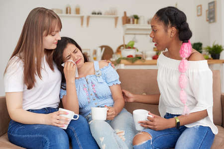 An unhappy woman talks about her problems to her friends at home. The concept of friendship and support.の写真素材