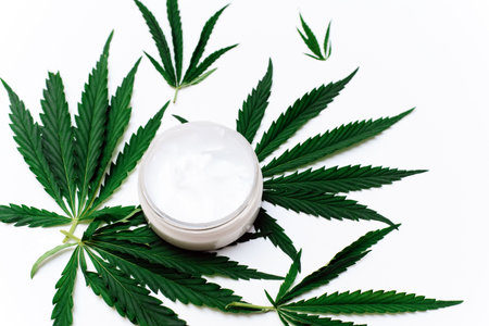 Moisturizing cream with hemp oil on a white background with hemp leaves. Natural skin careの写真素材