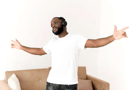 African American man enjoying music in wireless big headphones and dancing at home. Relax aloneの写真素材