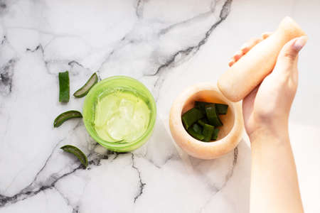 Hands of a woman mixing ingredients in mortar for natural aloe gel. sliced aloe leafの写真素材