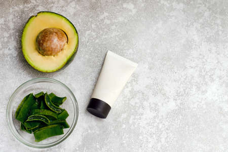 Moisturizing cream with aloe extract and avocado with a mockup on a gray background.