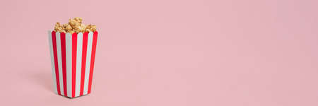 Movie Popcorn in striped bucket isolated on pink pastel background with copyspace. Template for blog. Web bannerの写真素材