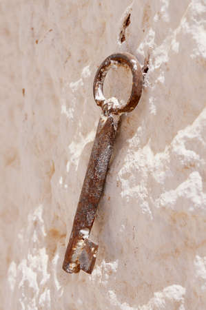 Close-up view of a rusty key on a rustic white stone wallの写真素材