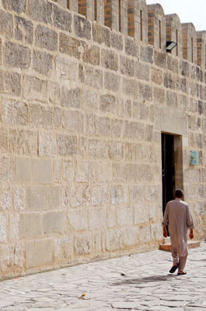 A tunisian man walking to the great mosque of Sousse in the medina of the city