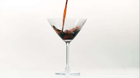 Red wine pouring into a glass against a white background