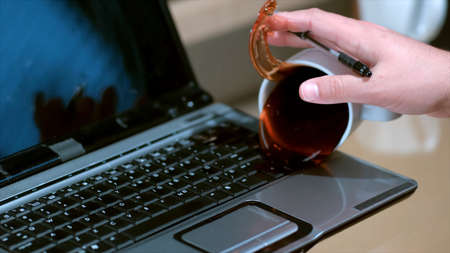 Spill coffee from white cup on the computer laptop keyboardの写真素材