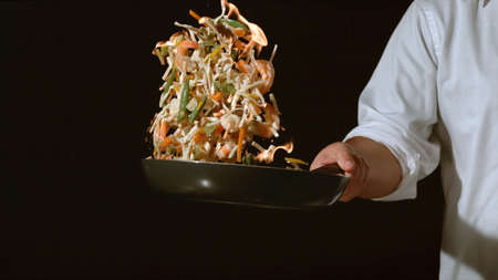 Chef man tossing vegetables in airの写真素材