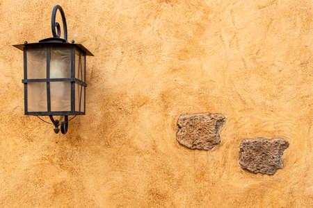 Rustic wall, orange and yellow textures with embed stone and iron lightの写真素材