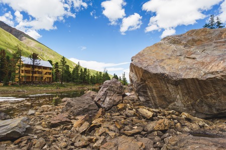 wooden hotel in the mountains near a large rock. Altai