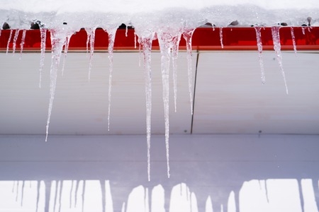 In the winter icicles are hanging on a building roofの写真素材