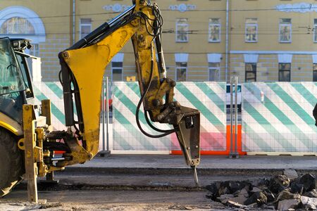 An excavator-mounted hydraulic jackhammer being used to break up concrete.の写真素材
