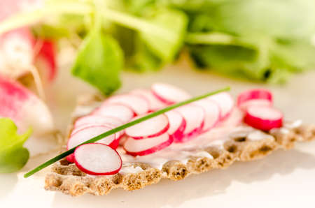Sliced radish on whole wheat crisps with cream cheese and chivesの写真素材