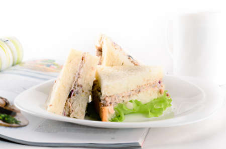 Breakfast of creamy tuna sandwiches with cup of tea and a journal on white backgroundの写真素材