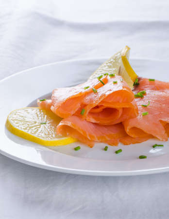 smoked salmon with lemon slices on white plateの写真素材