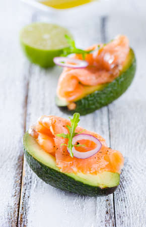Delicious appetizer of avocado and smoked salmon on white woodenの写真素材