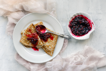 Pancakes with red huckleberry jam on concrete table. Pink gauze decoration. Top viewの写真素材