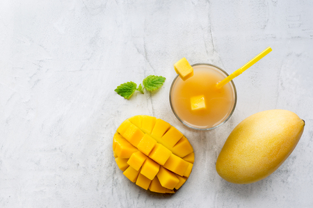 Healthy mango honey smoothie drink in a glass with mint on concrete table. Top view. Copy space.の写真素材