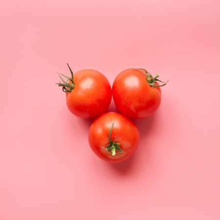 Ripe tomato on pink background. Creative concept. Square format. Top view.の写真素材