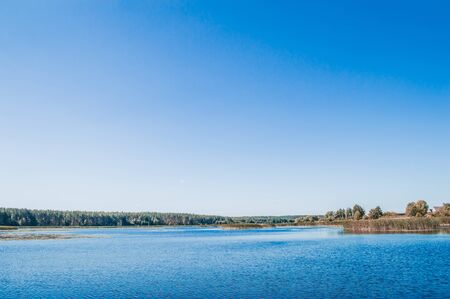 Landscape of lake with green forest in horizon and clear blue skyの写真素材