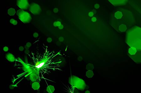 Burning sparkler in green and white light on a black background. Closeup photo of Christmas and new year sparkler. Can be used like a wallpaper or postcard.の写真素材