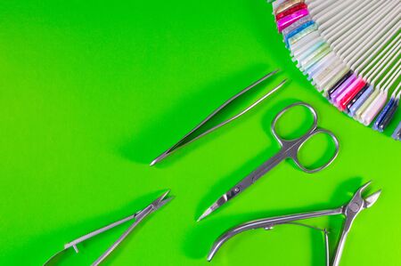 Manicure and pedicure tools on green background. Nail file, scissors, tweezers pusher, nippers. Medical tools top view.の写真素材