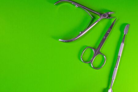 Manicure and pedicure tools on green background. Nail file, scissors, tweezers pusher, nippers. Medical tools top view.の写真素材