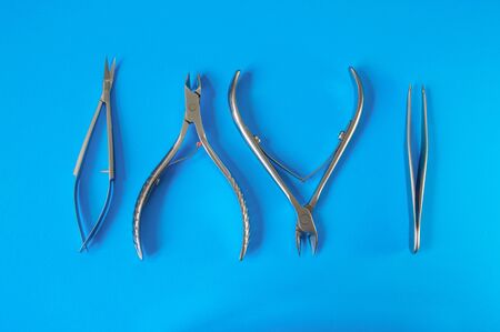 Manicure and pedicure tools on blue background. Nail file, scissors, tweezers pusher, nippers....