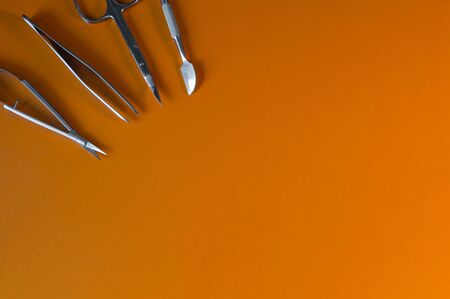 Manicure and pedicure tools on orange background. Nail file, scissors, tweezers pusher, nippers,...