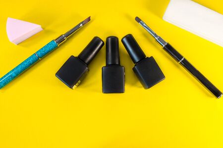 Manicure and pedicure tools on yellow background. Nail file, scissors, tweezers pusher, nippers, tassels. Medical tools top view.の写真素材