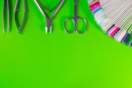 Manicure and pedicure tools on green background. Nail file, scissors, tweezers pusher, nippers. Medical tools top view.の写真素材