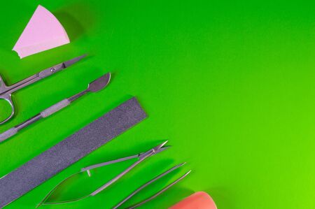 Manicure and pedicure tools on green background. Nail file, scissors, tweezers pusher, nippers. Medical tools top view.の写真素材