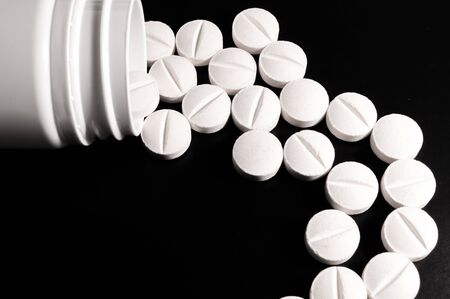 White medical pills and tablets on black background. Closeup photo of medical preparations with copy spaceの写真素材