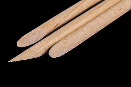 Wooden sticks for manicure and pedicure on black background. Medical tools in macro.の写真素材