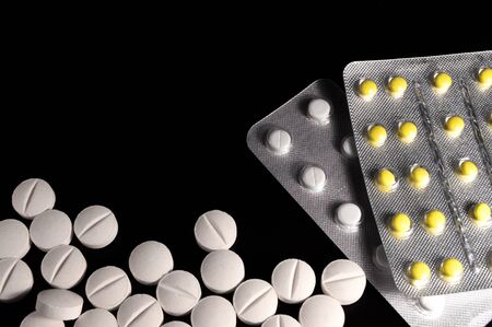 White medical pills and tablets on black background. Closeup photo of medical preparations with copy...