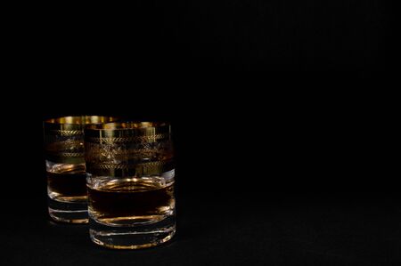 Short Glass of dark red whiskey, brandy or bourbon isolated on black background. Closeup photo of alcoholの写真素材