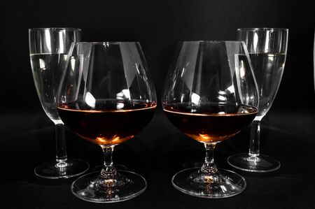 Glasses with different drinks. Brandy, whiskey, champagne or bourbon isolated on black background. Closeup photo of alcoholの写真素材