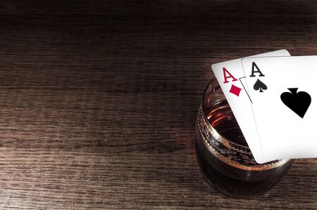 Glass of dark red whiskey, brandy or bourbon isolated on wooden dark background. Closeup photo of...