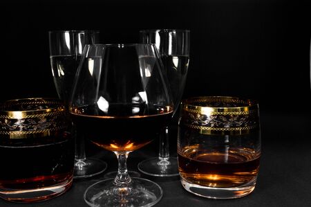 Glasses with different drinks. Brandy, whiskey, champagne or bourbon isolated on black background. Closeup photo of alcoholの写真素材