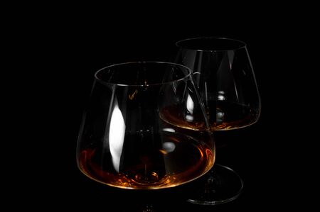 Glass of dark red for brandy,   whiskey or bourbon isolated on black background. Closeup photo of alcoholの写真素材
