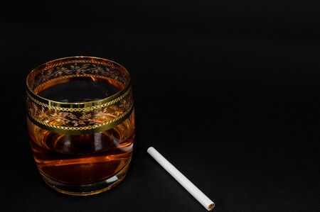 Glass of dark red whiskey, brandy or 
bourbon isolated on black background. Closeup photo of alcoholの写真素材