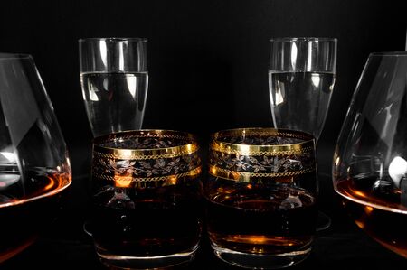 Glasses with different drinks. Brandy, whiskey, champagne or bourbon isolated on black background. Closeup photo of alcoholの写真素材