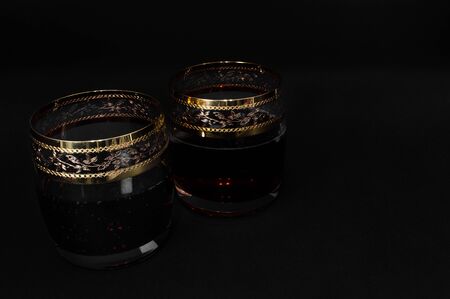 Glass of dark red whiskey with cola isolated on black background. Closeup photo of alcoholの写真素材