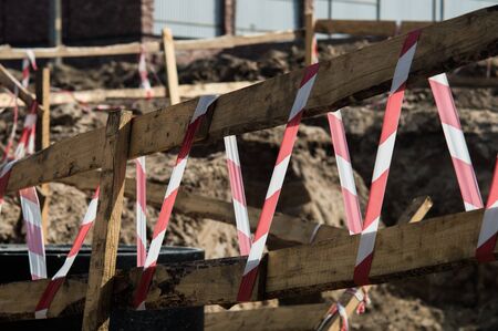 Wooden railing with a ribbon in red and white colors. Photo of road repairs with blurred background.の写真素材
